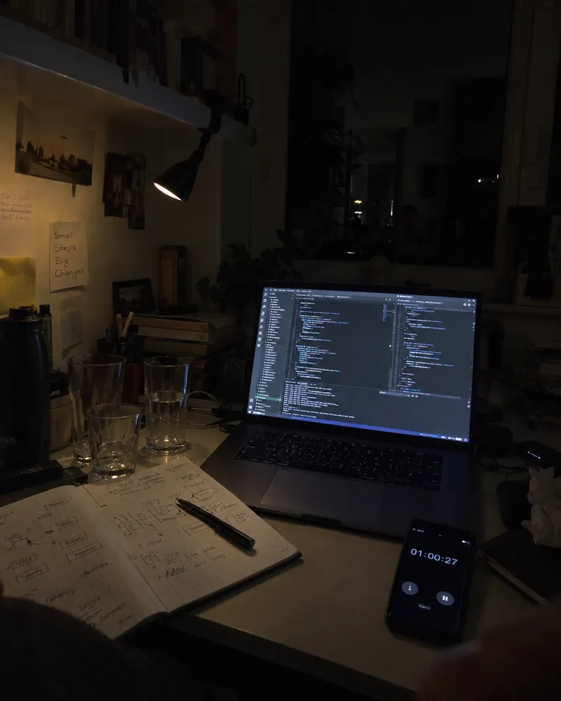 Mesa de estudio de madrugada: portátil con código, cuaderno y un temporizador en marcha