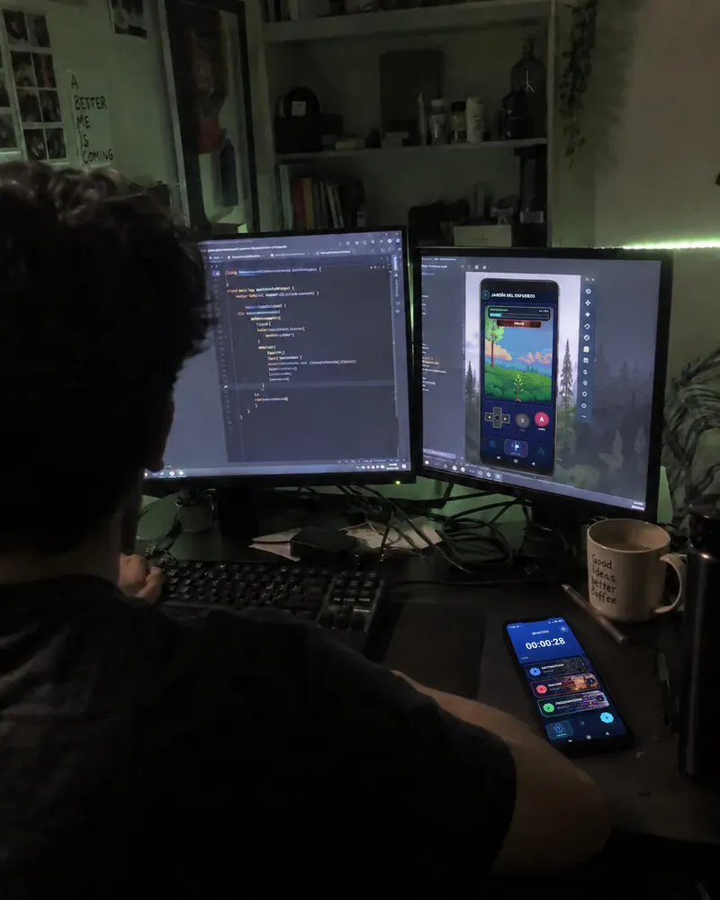 Dos monitores, uno con código y otro con el jardín de Lock In, y el móvil con una sesión en marcha